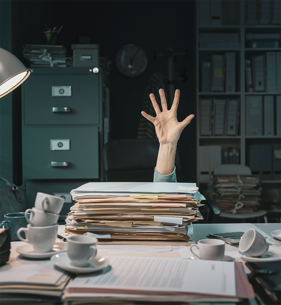 Hand showing above a busy desk